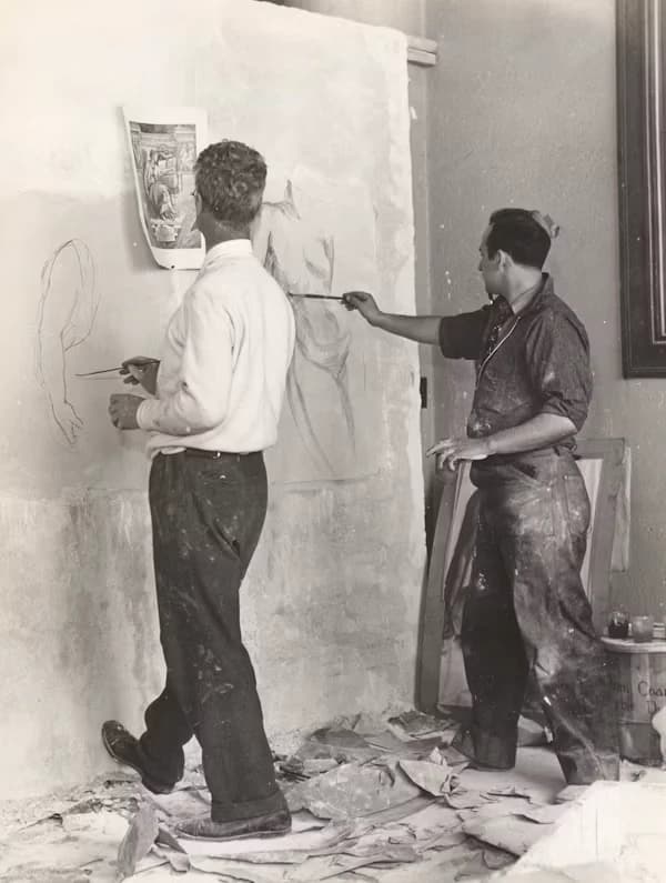 Dos restauradores trabajando en un dibujo sobre un muro, en blanco y negro